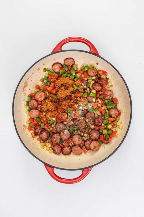 Sautéed sausage and chopped vegetables in a cast iron skillet.