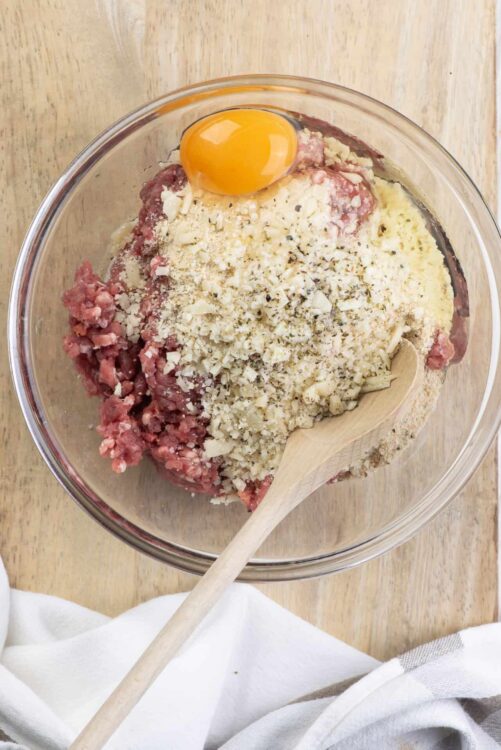 Ground meat, breadcrumbs, and egg mixture for meatloaf in a glass bowl.