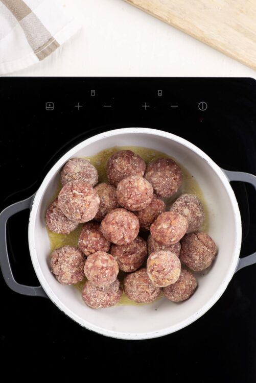 Savory meatballs cooking in skillet for baking or frying, home-cooked comfort food, close-up of raw meatballs with seasoning and oil, Baked Bree style.