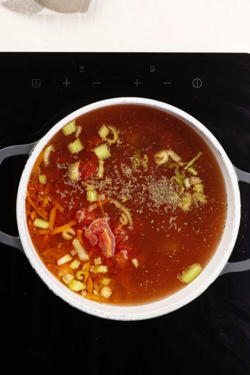 Hearty vegetable soup simmering in a pot on the stove, rustic homemade soup recipe.