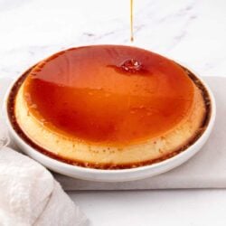 Creamy caramel flan being drizzled with caramel sauce on top.