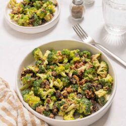 Roasted broccoli and garlic salad with walnuts and black beans on a white plate.