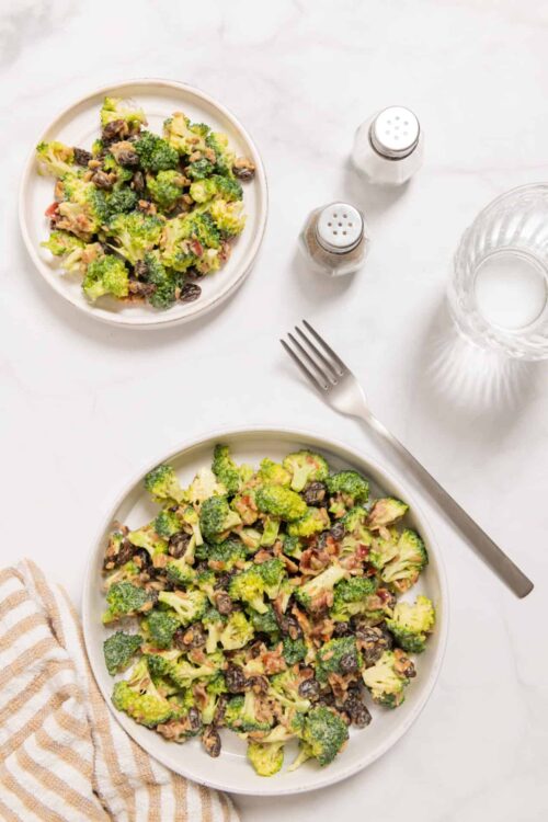 Roasted broccoli salad with black beans and bacon on white plates, healthy vegetable dish.
