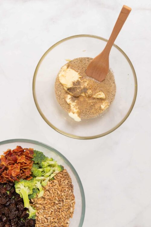 Creamy herb dip with butter, garlic, and spices in a glass bowl on white background.