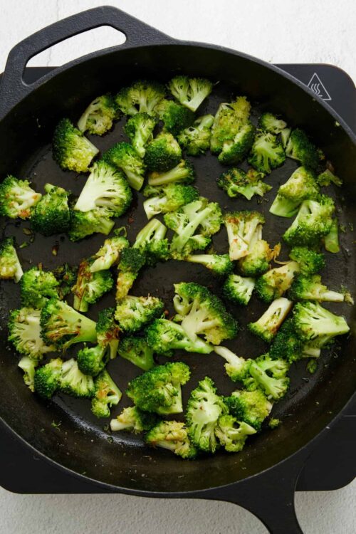 Roasted broccoli on black skillet for healthy vegetable dish.