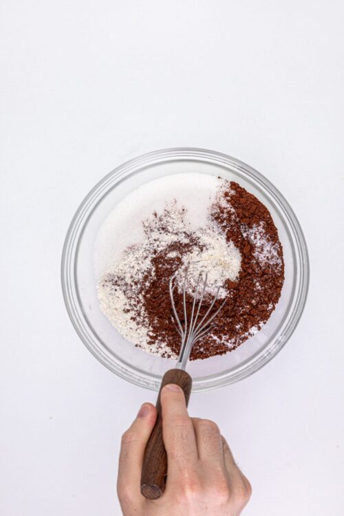 Fine cocoa powder and powdered sugar in a glass mixing bowl for baking recipes.