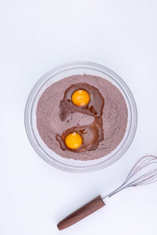 Eggs in a mixing bowl with chocolate batter for baking or dessert recipes.