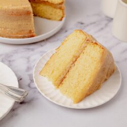 Fluffy vanilla sponge cake with buttercream frosting on a white plate.