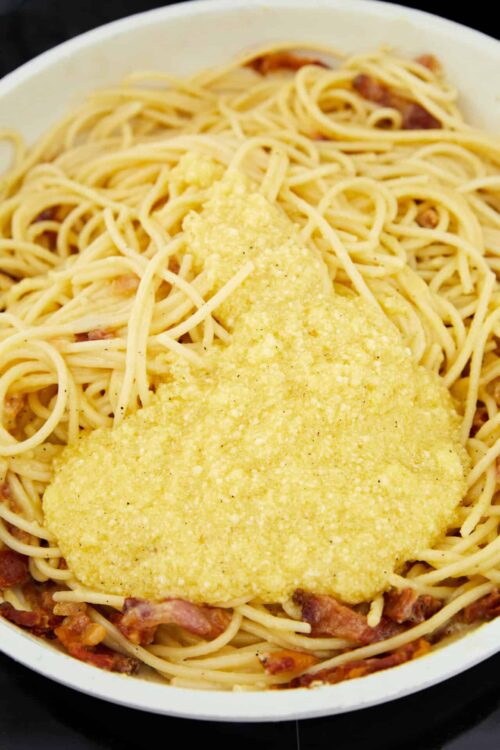 Creamy parmesan chicken Alfredo pasta dish with crispy bacon, served in a white bowl.