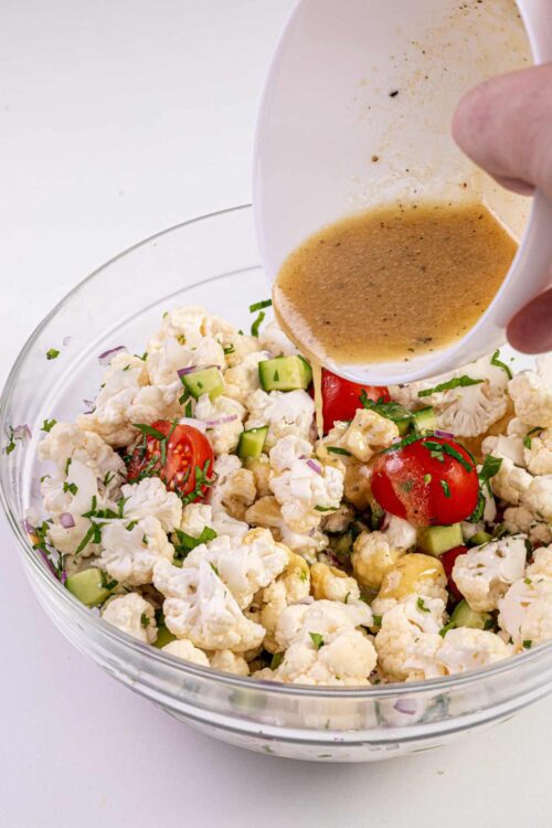 Fresh cauliflower salad with cherry tomatoes and cucumbers, topped with homemade vinaigrette dressing. Perfect for summer picnics and healthy meals.