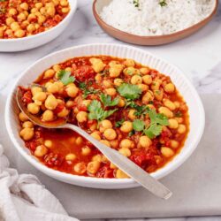 Chickpea stew with tomato sauce, garnished with cilantro, served with steamed white rice.