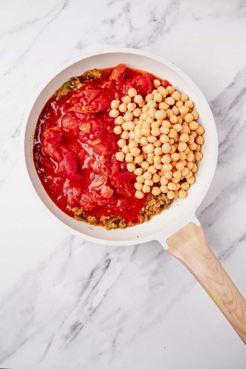 Savory vegetable and chickpea stew in a white skillet on marble surface.