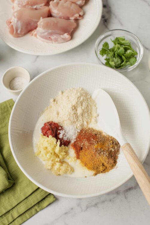 Diced chicken thighs with spices and ingredients in a mixing bowl for homemade chicken recipes.