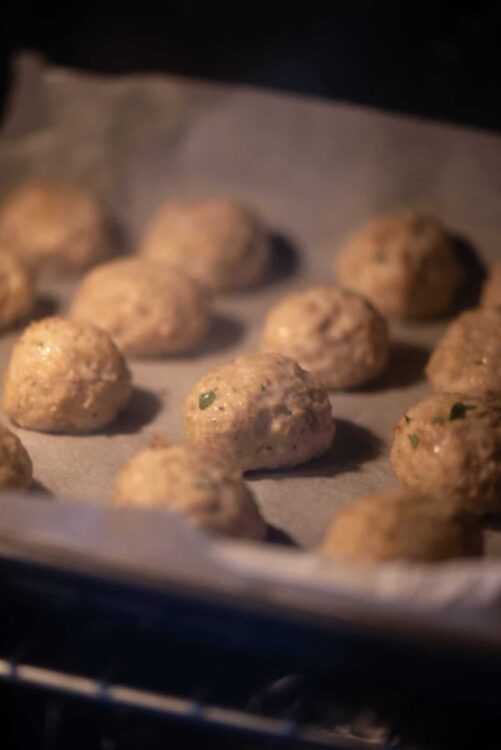 Fluffy homemade meatballs on baking sheet with parchment paper.