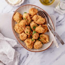 Crispy baked chicken nuggets on a ceramic plate garnished with parsley. Perfect for family meals or snacks.