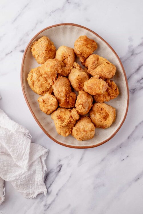 Golden crispy fried chicken bites on a ceramic plate.