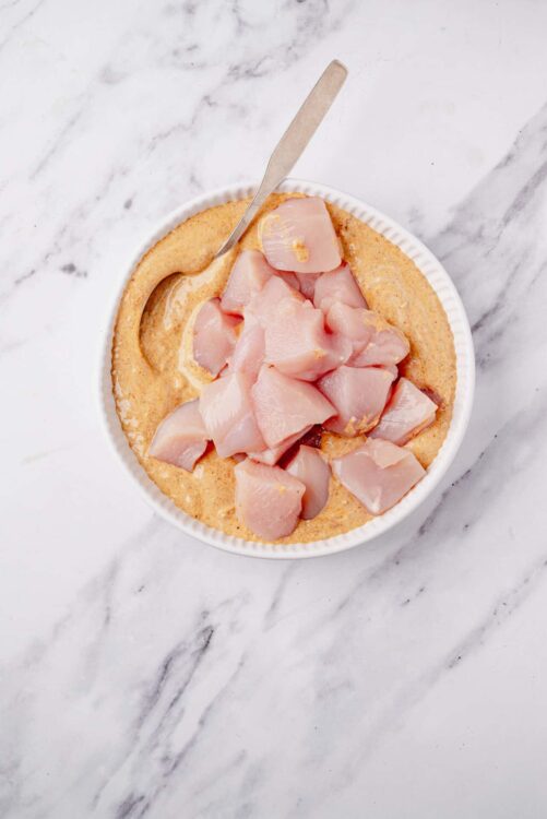 Raw chicken breast chunks in a baking dish for cooking or meal prep.