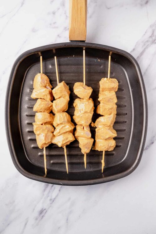 Marinated chicken skewers on grill pan for grilling or cooking.