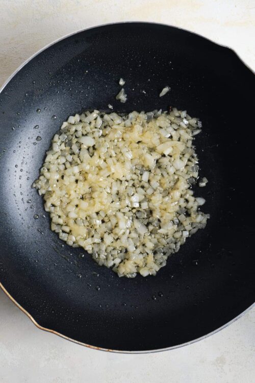 Sautéed diced onions in a non-stick skillet for cooking.