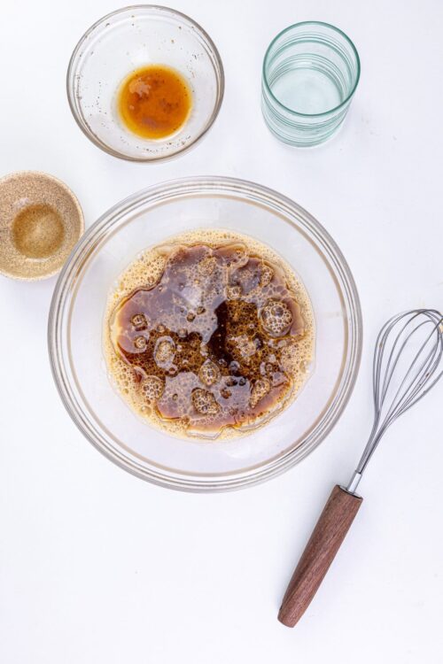 Baked Bree caramel sauce ingredients in glass bowl with whisk on white background.
