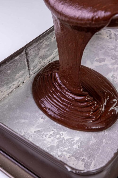 Rich melted chocolate being poured into a baking pan for desserts.