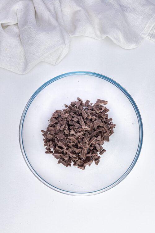 Dark chocolate chunks in glass bowl for baking recipes.