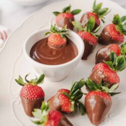 Fresh strawberries dipped in chocolate with a bowl of chocolate sauce for dipping. Perfect for desserts and sweet treats.
