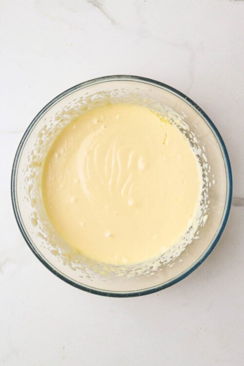 Creamy vanilla cake batter in a clear glass mixing bowl for baking recipes.