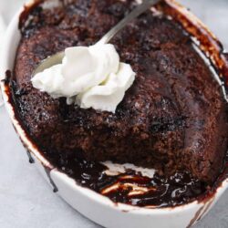 Decadent chocolate lava cake with whipped cream in a white baking dish.