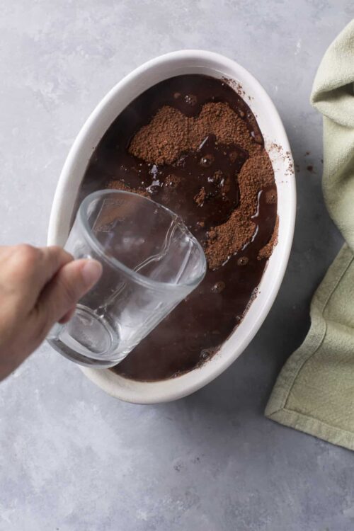 Rich hot chocolate with cocoa powder in an oval dish, ready to serve.