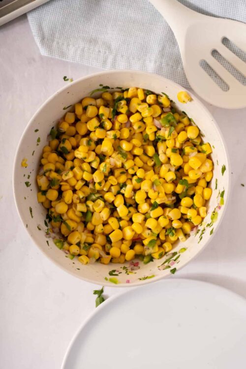 Bright yellow corn salad with chopped herbs and red onions.