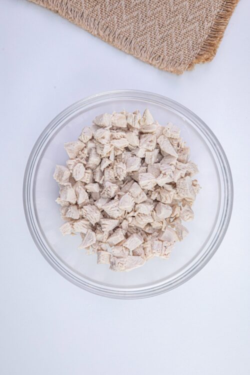 Cooked shredded chicken in a glass bowl ready for recipes.
