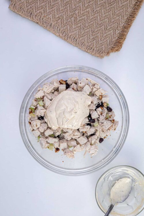 Cooked turkey salad with cream and dried cranberries in glass bowl, ready to serve.