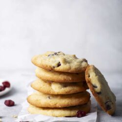 Freshly baked blueberry cookies stacked with dried berries scattered around.
