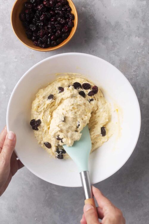 Sweet blueberry ice cream in a white bowl with fresh blueberries in a small bowl on a gray surface.
