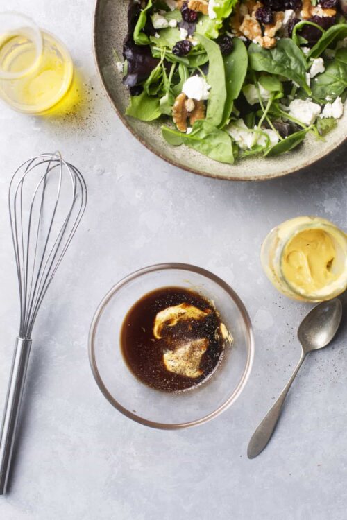 Buttermilk ranch salad dressing with fresh greens and walnuts on a rustic plate.