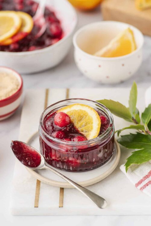 Fresh homemade berry fruit compote with lemon slices in a small glass jar, perfect for breakfast or dessert.
