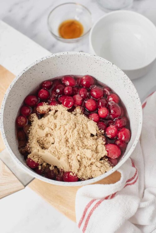 Fresh cranberries and brown sugar in a white mixing bowl for holiday baking.