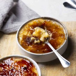 Butterscotch pudding in white ramekins with caramel sauce and whipped cream, bakedbree.com.