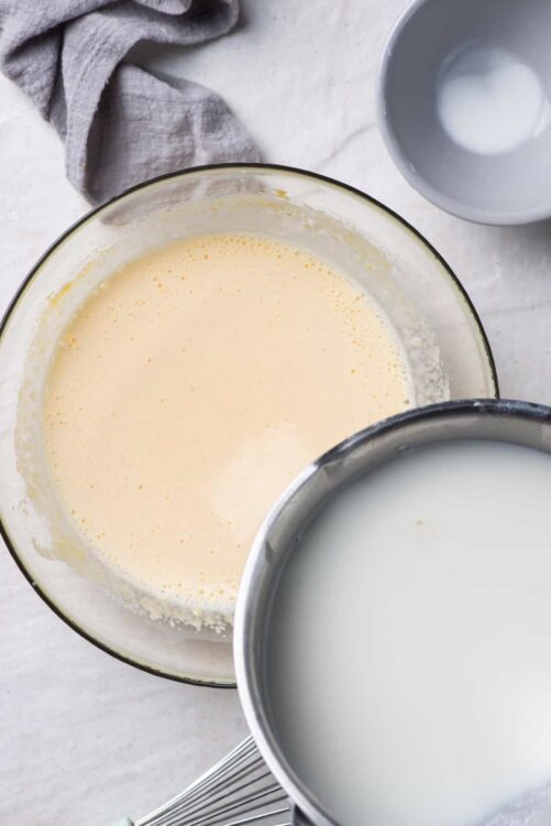 Whipped cream and milk for baking or recipes on a white surface.