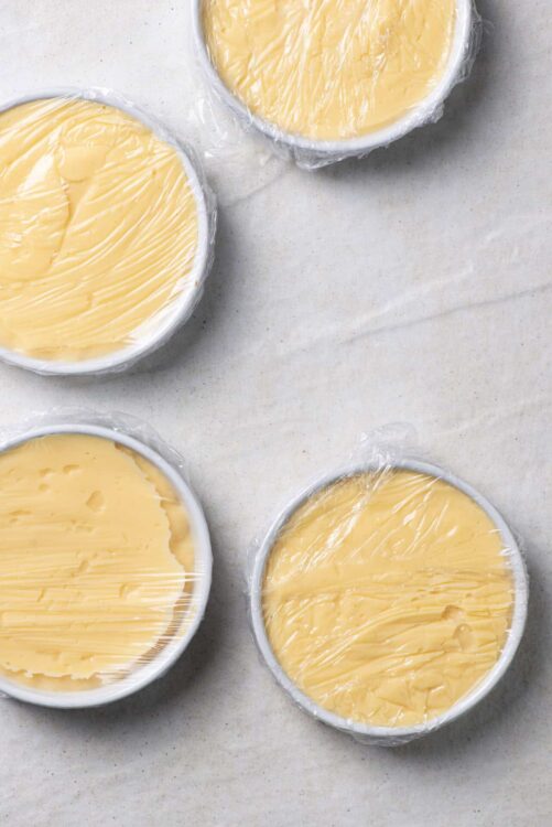 Cream cheese, butter, and cheddar cheese blocks in plastic wrap for baking.