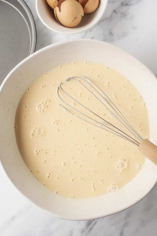 Smooth pancake batter in a mixing bowl with a whisk, ready for cooking.