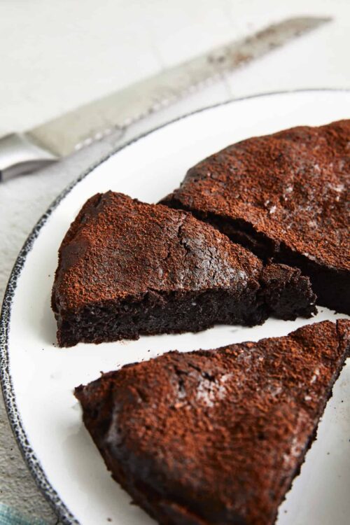 Decadent chocolate cake slices on a white serving plate, rich and moist dessert perfect for chocolate lovers.