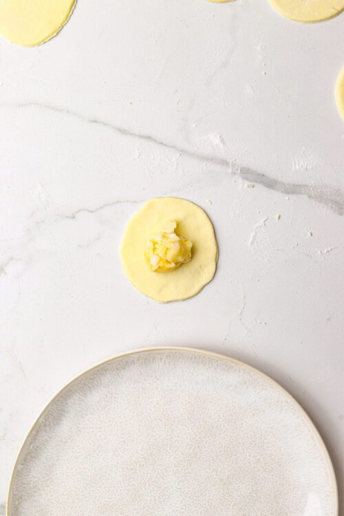 Buttery pie dough being filled with lemon curd for a homemade lemon tart recipe.
