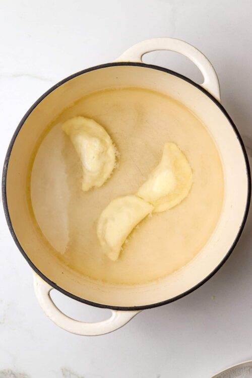 Buttered potatoes in a yellow enamel cast iron skillet.