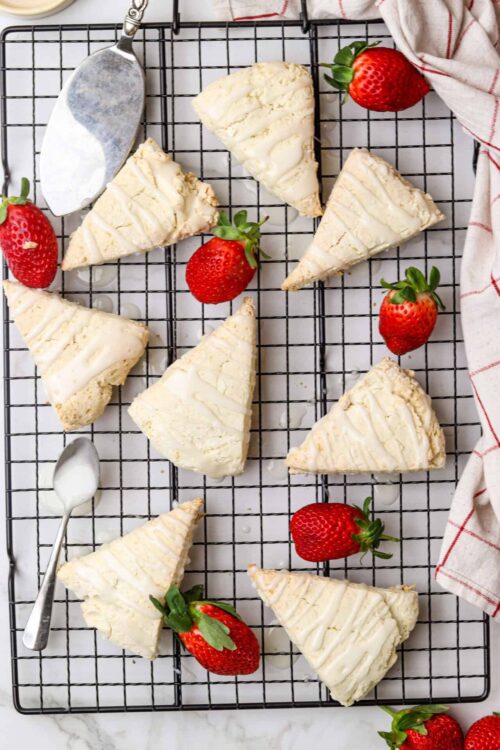 Creamy cheesecake slices garnished with strawberries on a cooling rack.