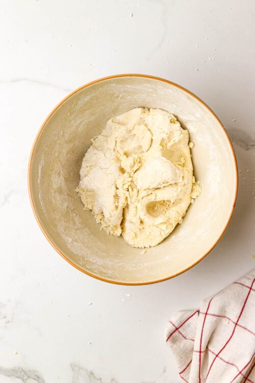 Buttery pie crust dough in a mixing bowl for baking recipes.