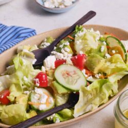 Fresh cucumber tomato salad with feta cheese on rustic plate.