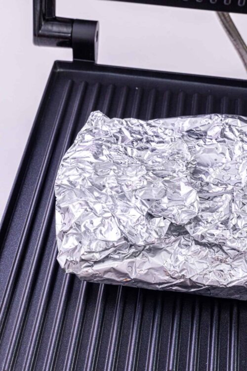 Foil-wrapped food on a grill griddle, ready for cooking or grilling.