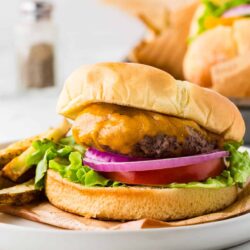 Juicy cheeseburger with lettuce, tomato, onion, and melted cheese on a toasted bun.
